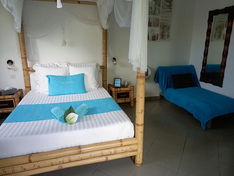 Chambre au lit à baldaquin en bambou, linge blanc et turquoise