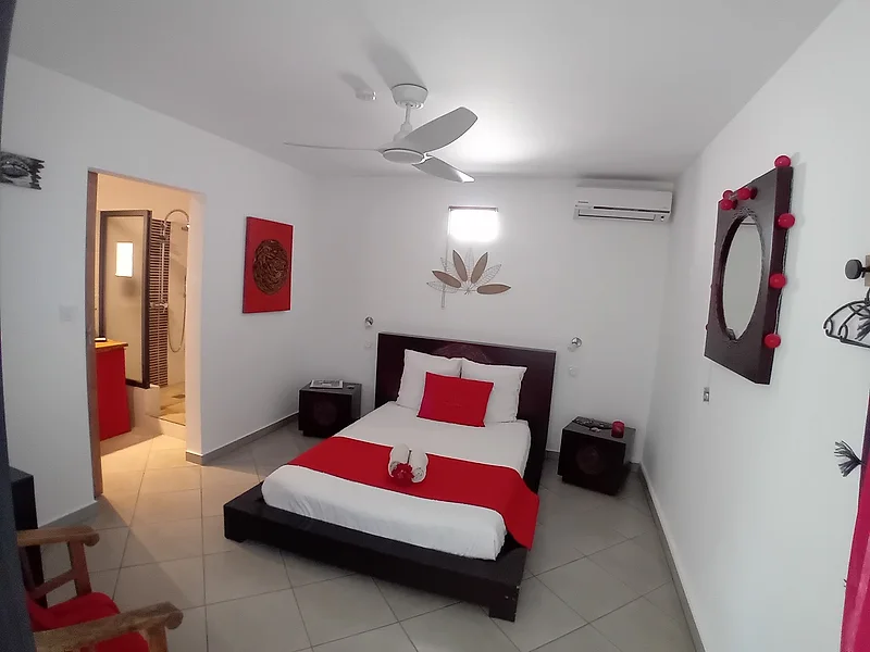 Chambre blanche et rouge, lit bas et ventilateur au plafond