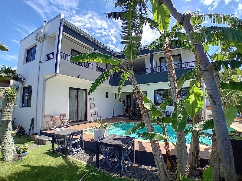 La maison vue du jardin, entre les bananiers, au-dessus de la piscine