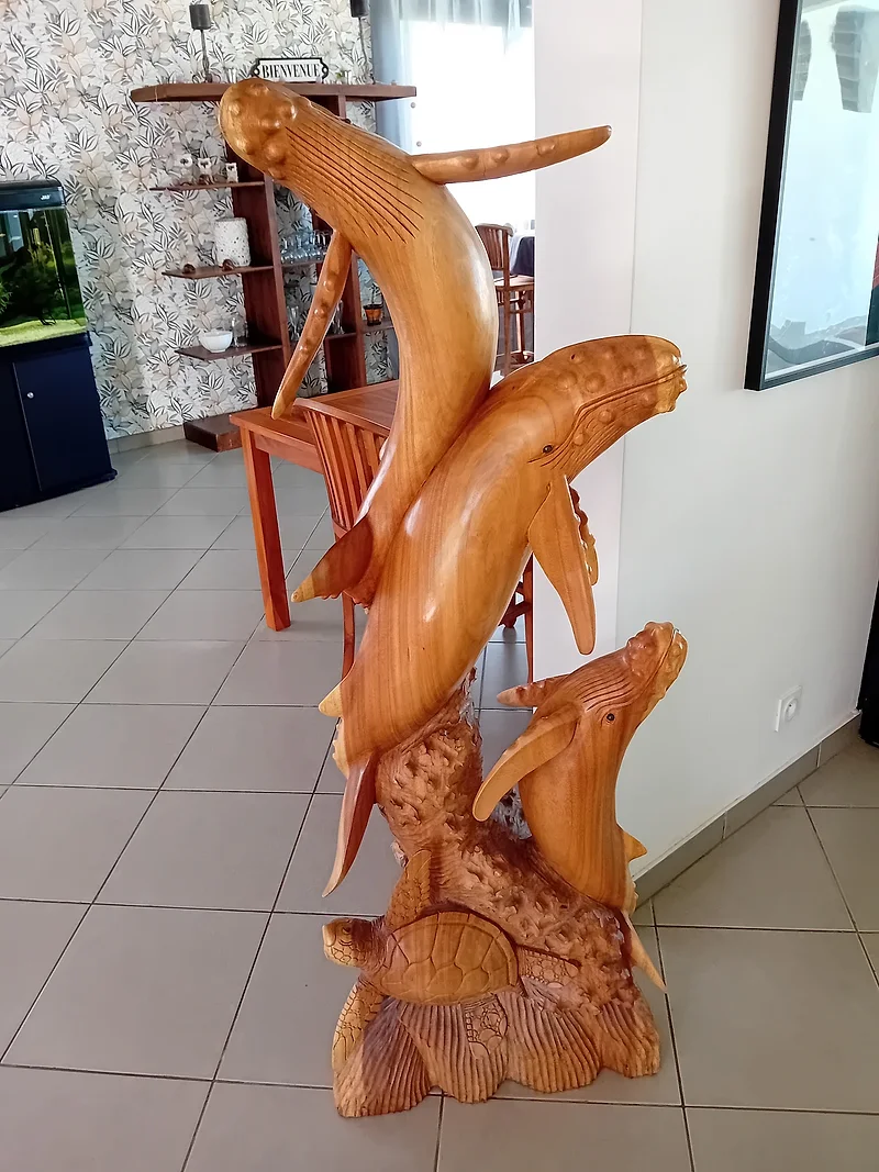 Des baleines et une tortue sculptées dans le bois, dans la salle de la maison